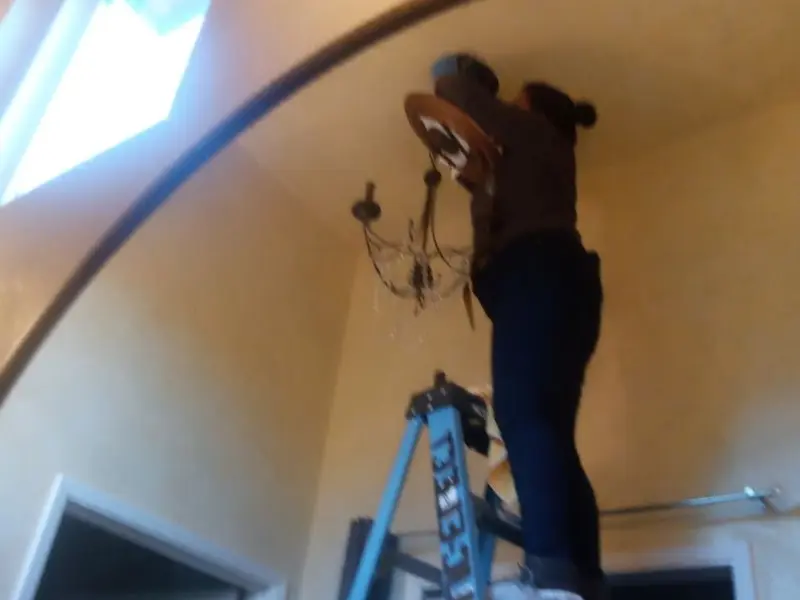 Electrician installing a chandelier in a Lake San Marcos residence